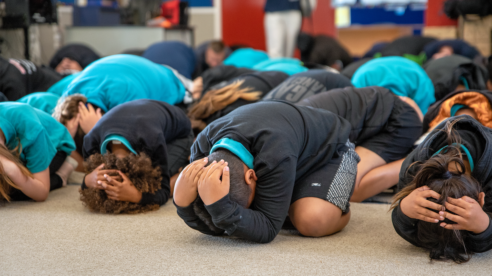 Primary school students doing Drop, Cover and Hold